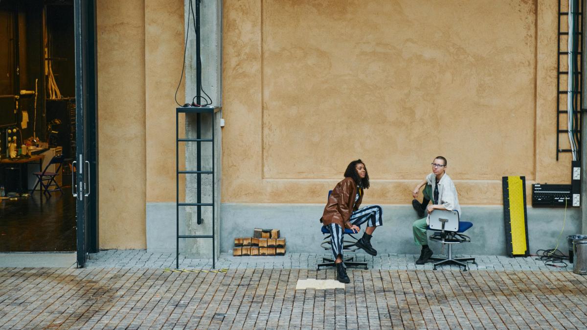 Kaksi opiskelijaa istuu Teatterikorkeakoulun Torilla.